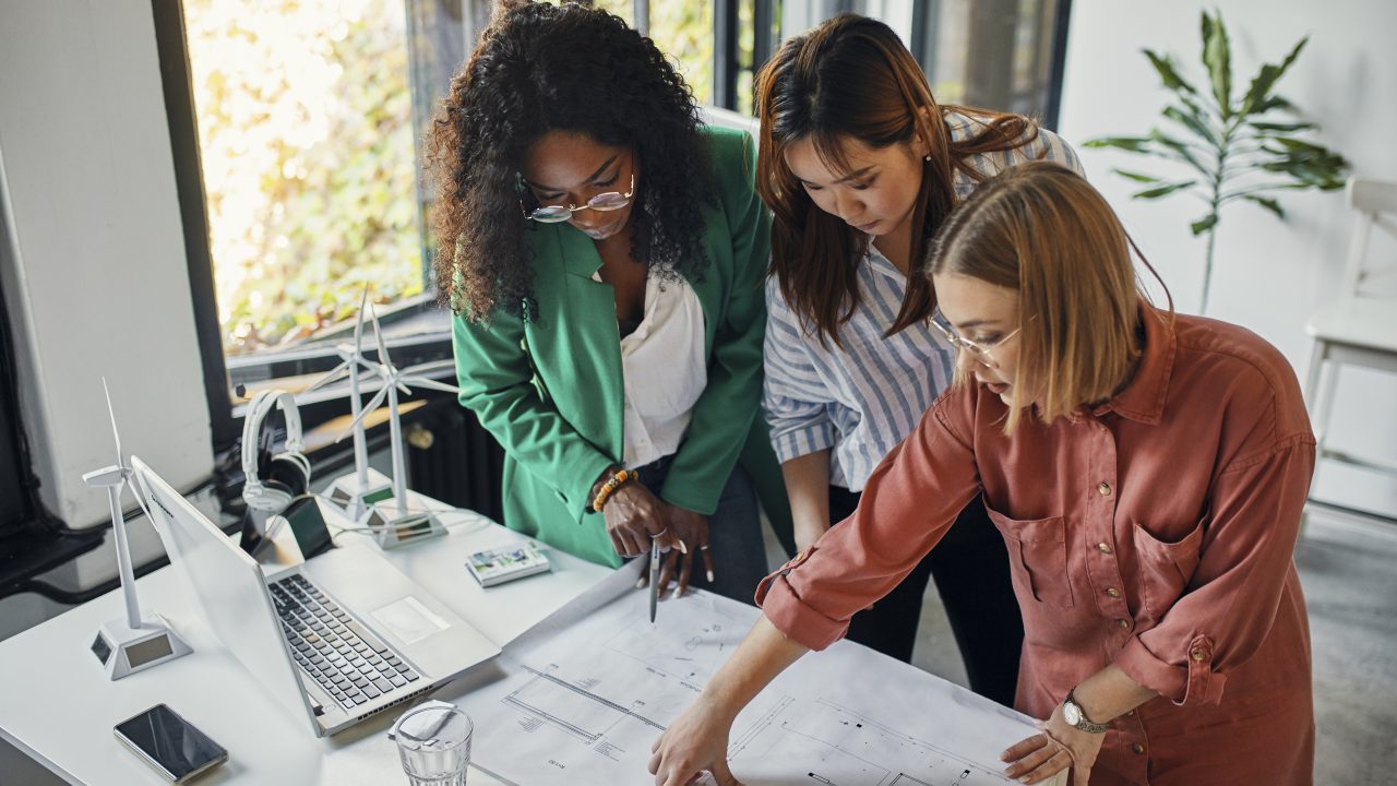 Businesswomen having a meeting in office with wind turbine models on table